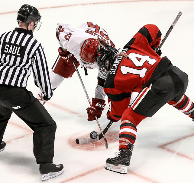 Zwei Eishockeyspieler von unterschiedlichen Teams mit dem Schiedsrichter kurz vor dem Spielbeginn auf dem Eisfeld