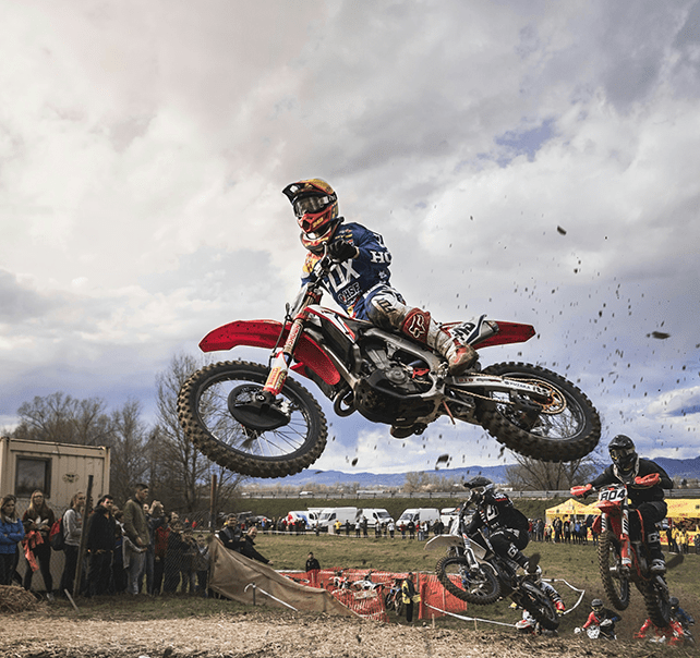 Motorcrossfahrer bei einem Sprung während einem Motocrossrennen. Rotes Motorrad.