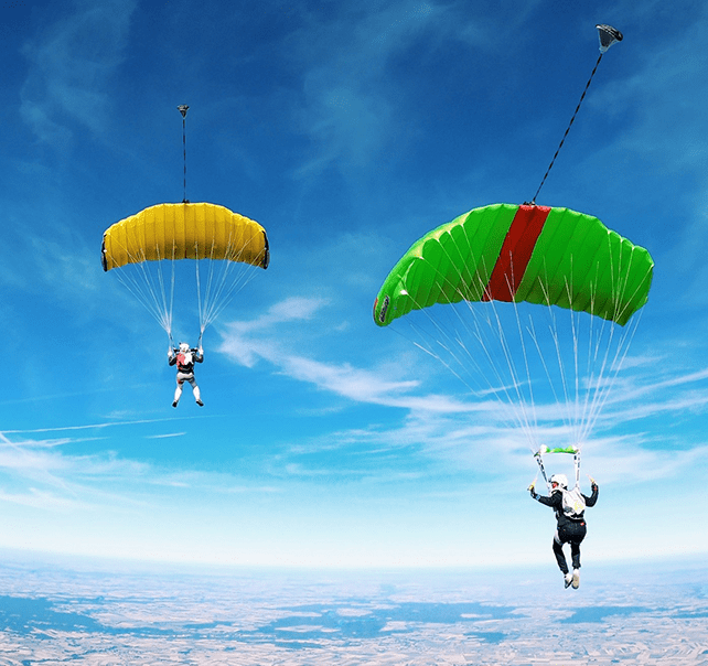 Zwei Fallsschirmfirmflieger mit bunten Fallschirmen bei blauem Himmel