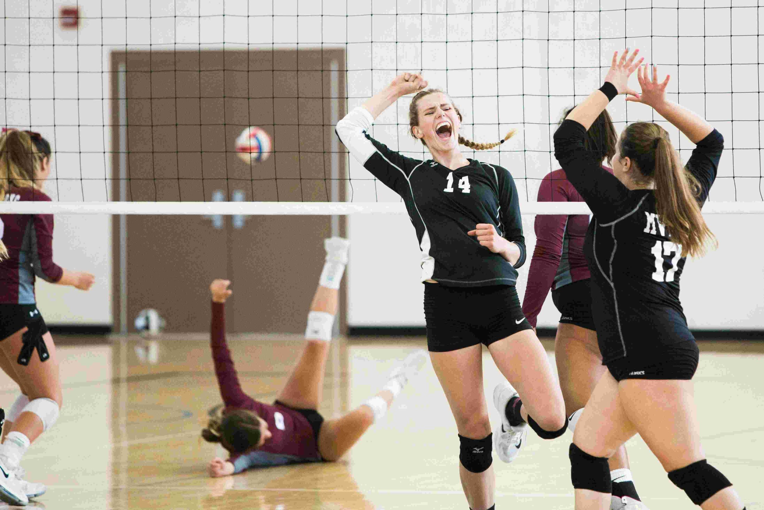 Fünf Frauen in schwarzen Trikots am Volleyball spielen in einer Turnhalle